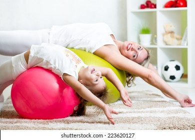 kid and mother doing gymnastic exercises with fitness ball at home