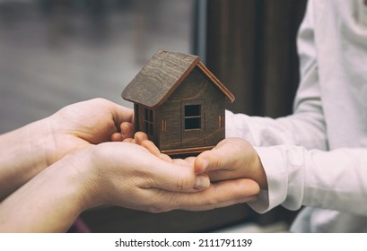 Kid And Mother Hold The Wooden Toy House. Adoption Concept. 