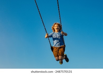 Kid on chain swing, having fun against blue sky. Carefree and freedom childhood. Active kid playing outdoors. Child at playground. Cute kid having fun on a playground outdoors in summer. Kid swinging. - Powered by Shutterstock