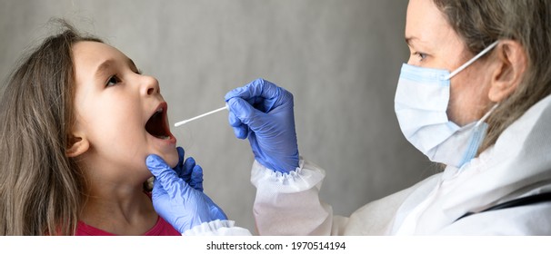 Kid Opens Mouth For COVID Or Monkeypox PCR Test, Doctor Holds Swab For Saliva Sample From Little Girl During Pandemic. Panoramic View Of Nurse And Child In School. Concept Of Corona Virus Testing.