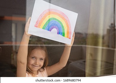 Kid painting rainbow during Covid-19 quarantine at home. Girl near window. Stay at home Social media campaign for coronavirus prevention, let's all be well, hope during coronavirus pandemic concept - Powered by Shutterstock