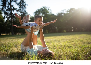 Kid In Park Playing Under Bright Sunlight With His Mother