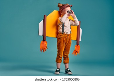 Kid Pilot Playing With Toy Jet Pack At Home. Success And Leader Concept. Isolated Blue Background. Copy Space