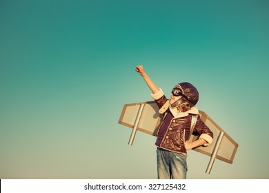 Kid pilot with toy jetpack against autumn sky background. Happy child playing outdoors