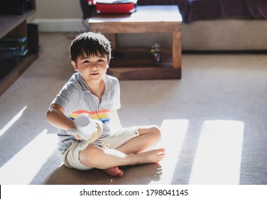 Kid Playing Alone With Dog Toy In Living Room With Morning Sun Shining Through The Window,Cute Child Having Fun Looking At Dust Particles Floating In The Air, New Normal Life Children Relaxing At Home