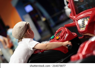 Kid Playing Arcade Simulator Machine At An Amusement Park