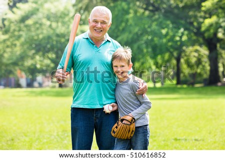 Kid Playing Baseball Game With Grandfather In Garden