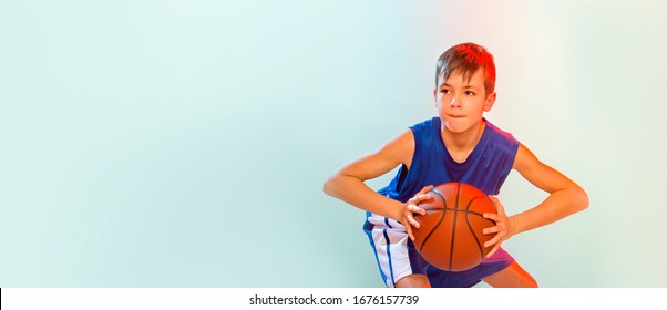 Kid playing basketball isolated on blue background in mixed light - Powered by Shutterstock