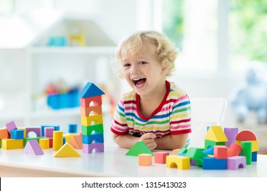 Kid playing with colorful toy blocks. Little boy building tower of block toys. Educational and creative toys and games for young children. Baby in white bedroom with rainbow bricks. Child at home. - Shutterstock ID 1315413023