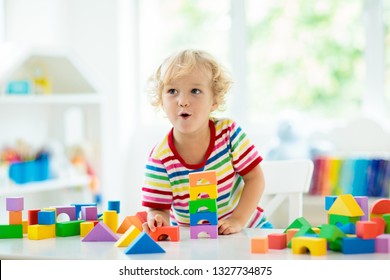 Kid playing with colorful toy blocks. Little boy building tower of block toys. Educational and creative toys and games for young children. Baby in white bedroom with rainbow bricks. Child at home. - Shutterstock ID 1327734875