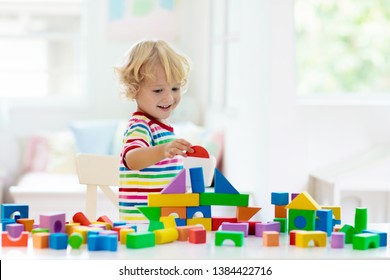 Kid playing with colorful toy blocks. Little boy building tower of block toys. Educational and creative toys and games for young children. Baby in white bedroom with rainbow bricks. Child at home. - Shutterstock ID 1384422716
