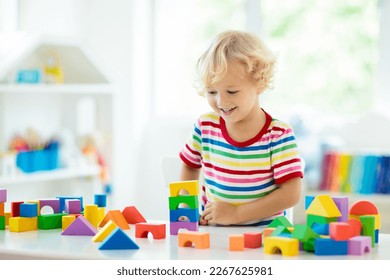 Kid playing with colorful toy blocks. Little boy building tower of block toys. Educational and creative toys and games for young children. Baby in white bedroom with rainbow bricks. Child at home. - Powered by Shutterstock