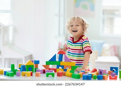 Kid playing with colorful toy blocks. Little boy building tower of block toys. Educational and creative toys and games for young children. Baby in white bedroom with rainbow bricks. Child at home. - Shutterstock ID 2267634147