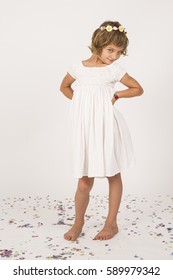 kid playing with confetti in the studio. Fun, lifestyle. Casual clothing. little girl portrait. indoors, confetti on the floor. white  background