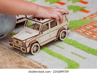 Kid Playing Eco Wood Puzzle Car 3d At Home On Carpet With Road At Home. The Concept Of Learning Traffic Rules Childhood