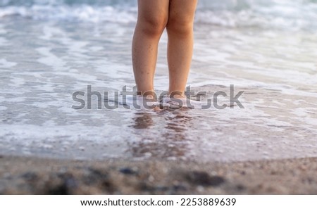 kid playing on beach sand running digging using plastic toys crab lobster seahorse shell shape rake and sprinkler.sunny summer vacation day child preschooler boy feet legs in water waves hitting sole