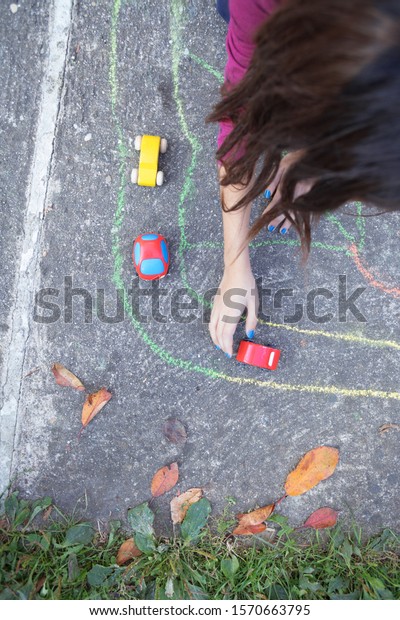 kid playing\
with small car toys on the\
playground