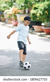 Kid Playing Soccer Alone In On The Road And Learning How To Bounce The Ball