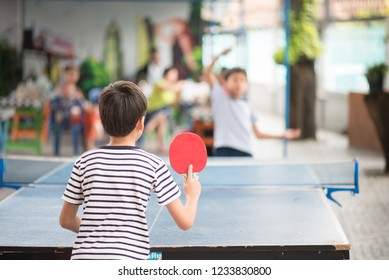 Kid playing table tennis outdoor with family