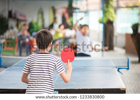 Kid playing table tennis outdoor with family