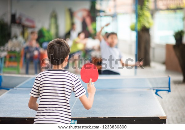 Kid playing\
table tennis outdoor with\
family