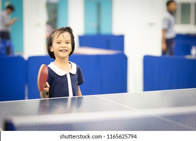 Kid Playing Table Tennis Sport Concept, Asian Kids Happy Playing Table Tennis Or Ping Pong In Gym For Exercise. She Holing Racket On Right Hand And Smile For Play And Hitting Ball On Table 