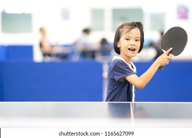 Kid Playing Table Tennis Sport Concept, Asian Kids Happy Playing Table Tennis Or Ping Pong In Gym For Exercise. She Holing Racket On Right Hand And Smile For Play And Hitting Ball On Table