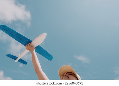 Kid playing with toy airplane. Children dream of travel by plane. Happy child girl has fun in summer vacation by sea and mountains. Outdoors activities at background of blue sky. Lifestyle moment. - Shutterstock ID 2256048691