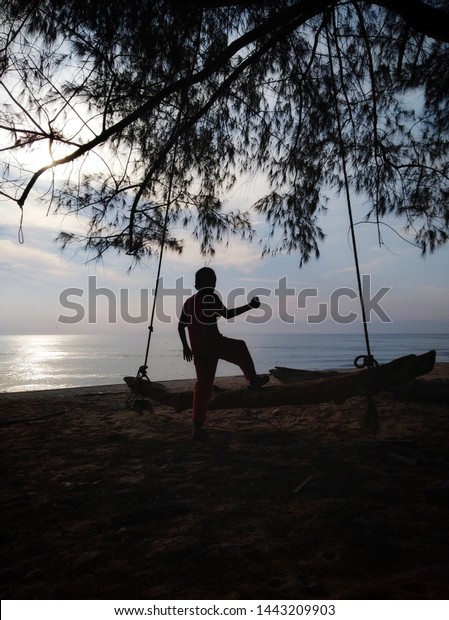 kid\
playing wooden swing seat under the tree at\
beach
