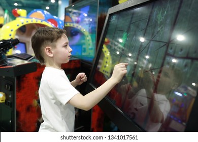 Kid Plays Game On Large Touch Screen In Amusement Park