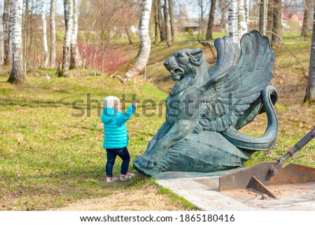 Kid pointing at Griffon statue in Maryino park near Tosno, Leningrad region, Russia