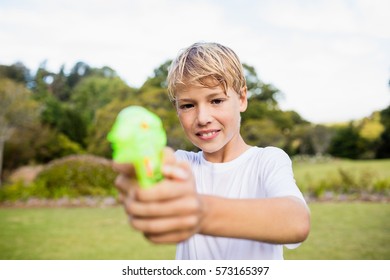 Kid posing at camera during a sunny day with his water gun at park