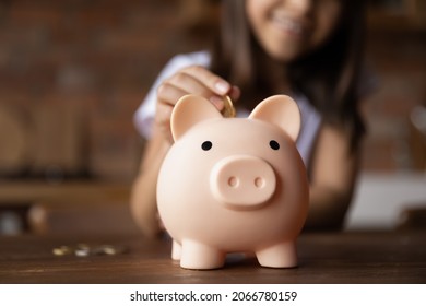 Kid putting coin into pink piggy bank. Happy girl saving money, cash for purchase learning economy, business, investment, planning future counting budget. Financial education concept. Close up - Powered by Shutterstock