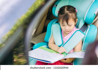 Kid Reading A Book Wait For Mother And Sit In The Car Seat For Safety.