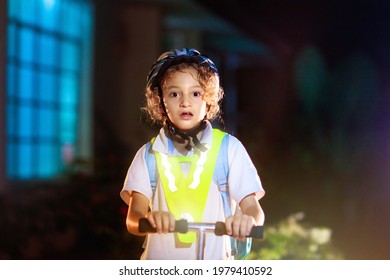 Kid In Reflective Vest In Darkness. Safety On Dark City Streets For School Children. Safe Way Home At Night Or In The Evening. Fluorescent Stripes On Kids Clothing And Backpack. Boy Walking At Dusk.