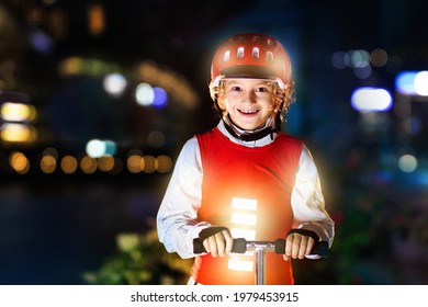 Kid In Reflective Vest In Darkness. Safety On Dark City Streets For School Children. Safe Way Home At Night Or In The Evening. Fluorescent Stripes On Kids Clothing And Backpack. Boy Walking At Dusk.