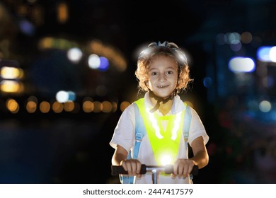 Kid in reflective vest in darkness. Safety on dark city streets for school children. Safe way home at night or in the evening. Fluorescent stripes on kids clothing and backpack. Boy walking at dusk. - Powered by Shutterstock