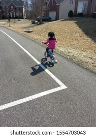 Kid Riding A Bicycle In The Bike Lane Of A Suburban Neighborhood