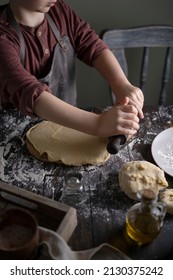 Kid Rolling Dough On Wooden Table With Ingredients Flour, Oil, Salt, Dark Background. Copy Space. Home Bakery Concept, Kitchen Cooking Story.