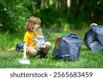 Kid in rubber gloves with trash bag clean up garbage on forest outdoor. Eco, environment conservation. Recycle pollution. Kid boy collecting garbage and plastic trash. Save environment. Eco kids.