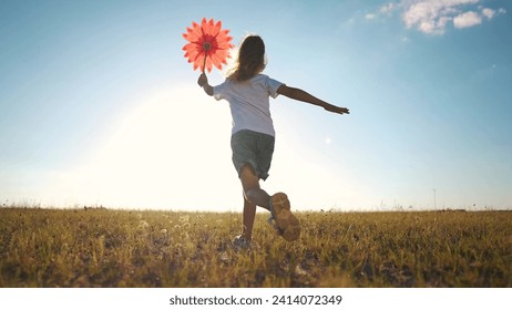 kid run pinwheel. little baby girl silhouette play with windmill toy wind in the park. happy family kid dream concept. baby girl play toy pinwheel glare of the sun at sunset in the park fun - Powered by Shutterstock