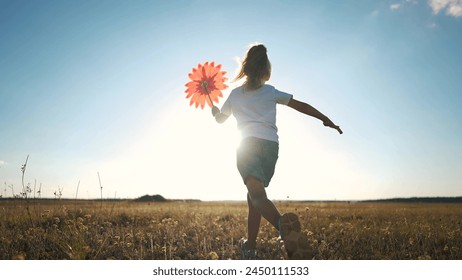 kid run pinwheel. little baby girl silhouette play with windmill toy wind in the park. happy family kid dream concept. baby girl play toy pinwheel glare of the sun at sunset in the fun park - Powered by Shutterstock