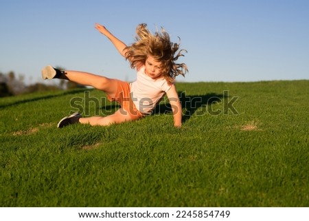 Kid runs through the spring grass and falling down on the ground in park. Moment of the fall down. Little child tripped and falls down. Fall risk for children. The moment of the fall. Clumsy kid.