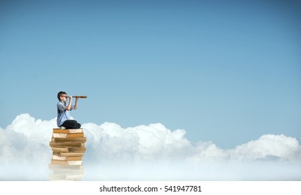 Kid Of School Age Sitting On Pile Of Books And Looking In Spyglass