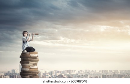 Kid of school age sitting on pile of books and looking in spyglass - Shutterstock ID 603989048