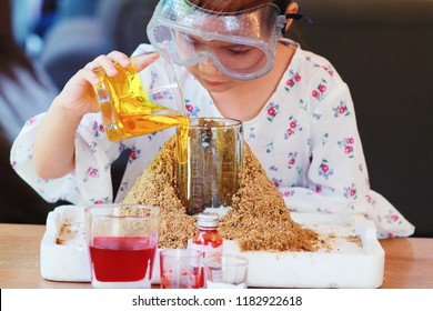 Kid Science Experiment Of Volcano Or Baking Soda And Vinegar Volcano Eruption For Kid.Girl With Eyeglasses Pouring Dish Soap To The  Container Of Baking Soda,mixed And Poring Vinegar For Volcano Labs.