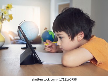 Kid self isolation using tablet for his homework,Child doing using digital tablet searching information on internet during covid 19 lock down,Home schooling,Social Distance,E-learning online education