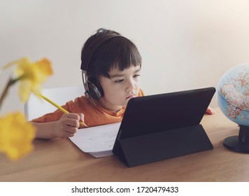 Kid Self Isolation Using Tablet For His Homework,Child Doing Using Digital Tablet Searching Information On Internet During Covid 19 Lock Down,Home Schooling,Social Distance,E-learning Online Education