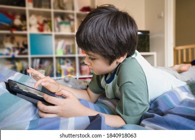 Kid self isolation using tablet for his homework,Child lying in bed  using digital tablet searching information on internet,Home schooling, Social Distance, E-learning online education