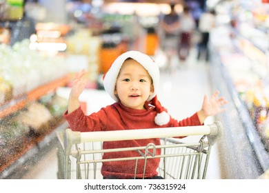 A Kid Is Shopping In Supermarket With His Parent For Prepare The Christmas Party.